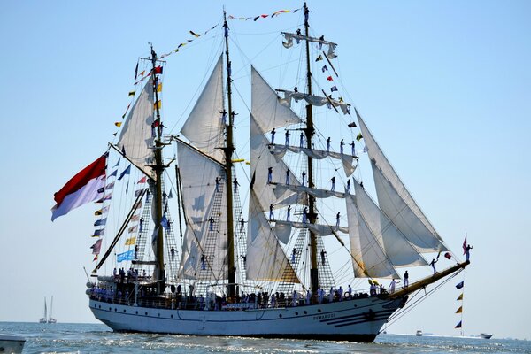 Segelschiff mit Menschen darauf im Meer vor dem Hintergrund des klaren blauen Himmels