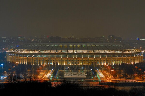 Le stade couve monumentalement les lumières de la nuit