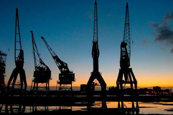 Grues dans le port sur fond de ciel coucher de soleil