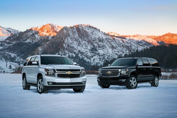 Dos SUV de la empresa Chevrolet están en la nieve, donde en el fondo se ven hermosas montañas nevadas