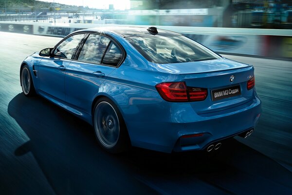 Une voiture BMW bleue roule sur une route de course