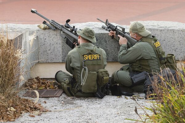 Scharfschützen mit Waffen hinter einer Betondecke