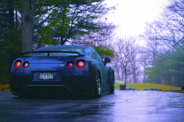 Nissan azul, r35, en la lluvia en la vista trasera de la carretera