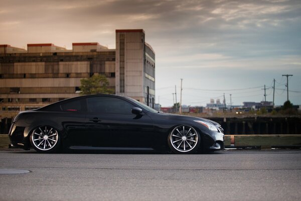 Negro infiniti g37 en sintonía con el fondo de la zona industrial