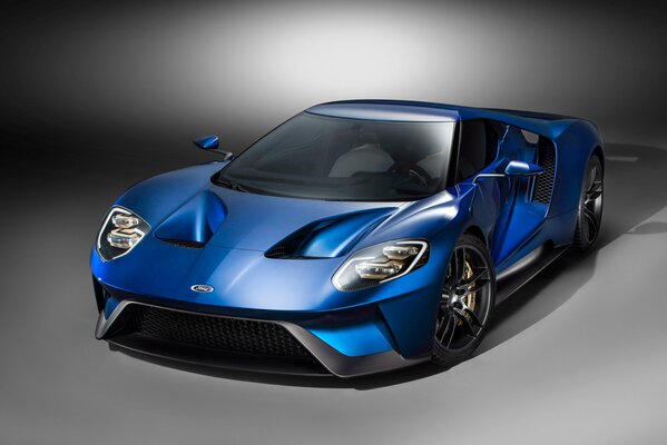 Синий ford gt полубоком на сером фоне