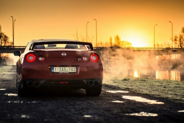 Rosso sportivo nissan R35 gt - r sullo sfondo del tramonto