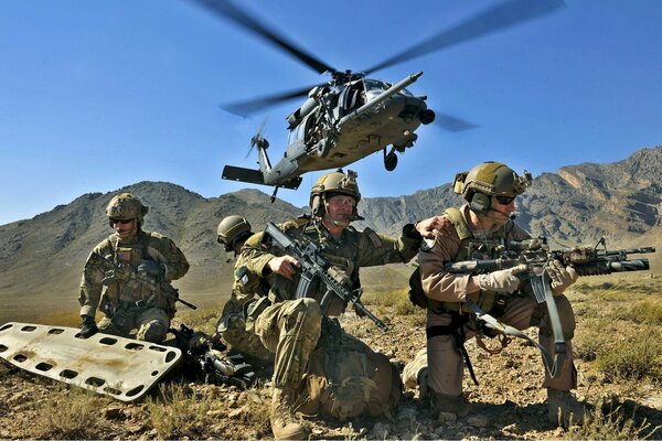 Three soldiers with a stretcher on the background of a helicopter