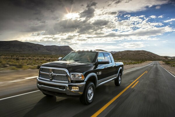 Ram Heavy Duty rushes along the highway against the background of hills and mountains