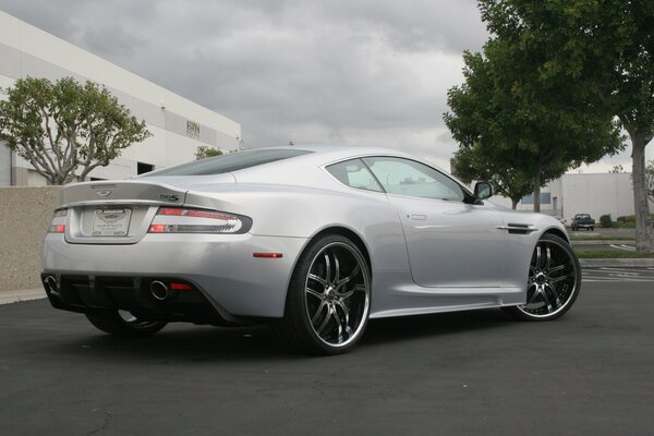 Silver aston martin near the trees