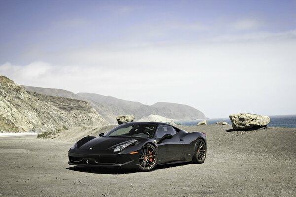 Black Ferrari on the background of mountains and blue sky