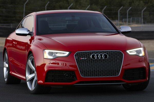 Blood-red audi rs5 on the background of a fence