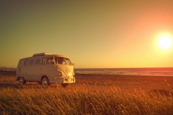 A Volkswagen trailer stands in a field at sunset