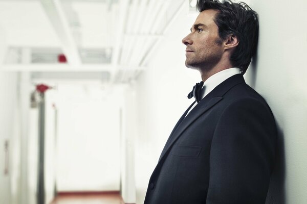 Actor Hugh Jackman in a suit against the wall