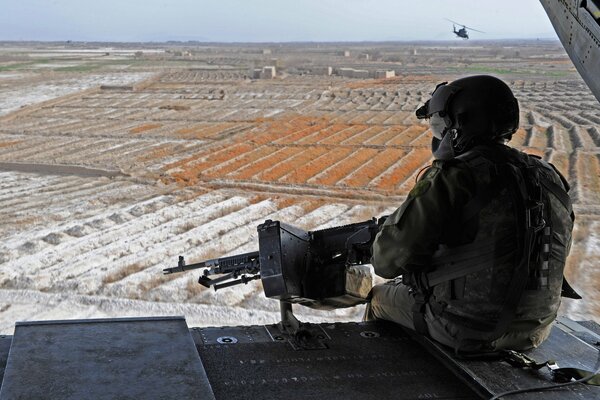 Un soldado con una ametralladora mirando hacia el horizonte