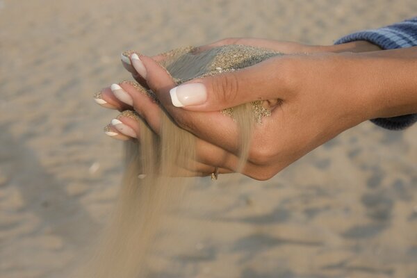 Beach sand flowing through women s fingers