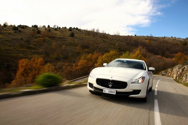 Maserati se mueve rápidamente en el paisaje de otoño