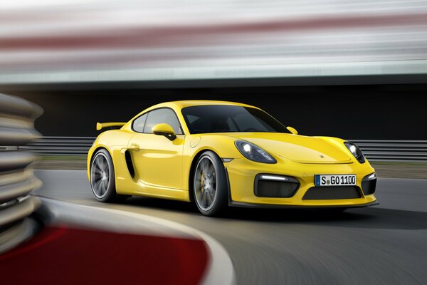 Yellow Porsche Cayman enters the turn at high speed