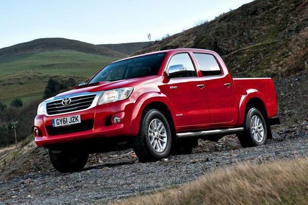 Red pickup truck rides in the mountains of Great Britain