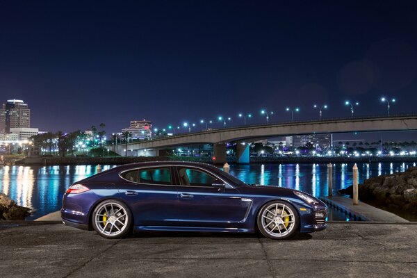 Bleu porsche panamera s vue latérale sur la ville de nuit