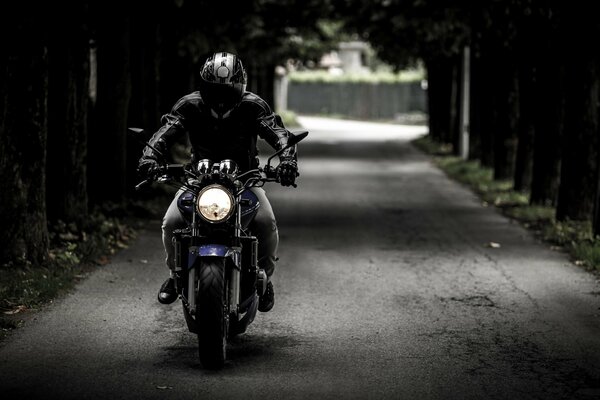 Un motorista con casco en una motocicleta va por la carretera