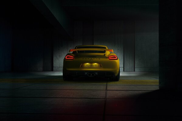 Yellow Porsche gt4 in a dark room rear view