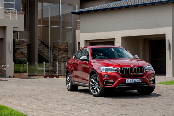 A red bmw with Guadeloupe plates standing near the garage