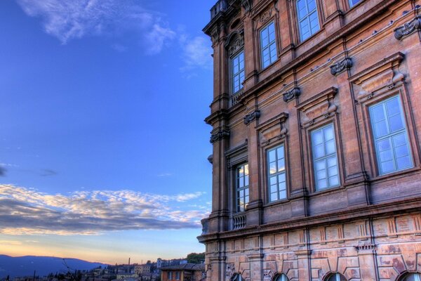 Ein architektonisches Gebäude, in dessen Fenstern sich der Himmel spiegelt