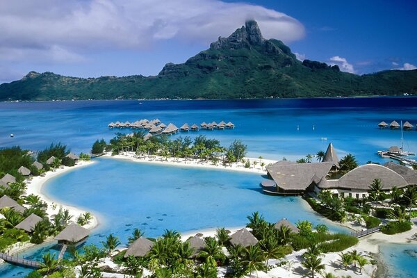 Palm trees, beach, mountains, clouds at a resort in the ocean