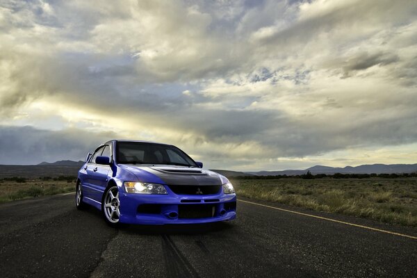 Mitsubishi azul en el camino entre las nubes