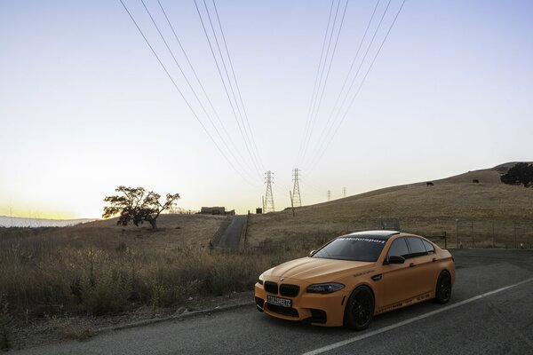 BMW M5 amarillo en el fondo de las líneas eléctricas