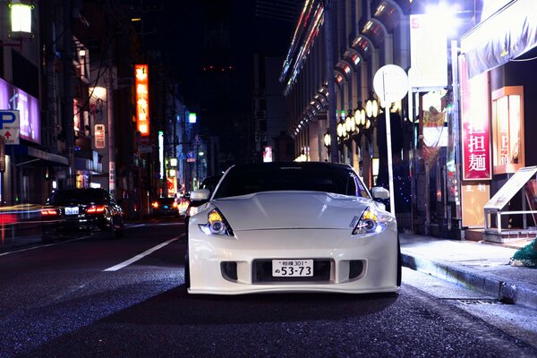 Nissan 370Z bianca con ruote Fossen sta sulla strada di notte