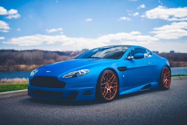 Sporty Aston Martin on the road against the background of the lake