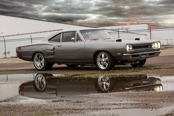 A gray car reflected in a puddle