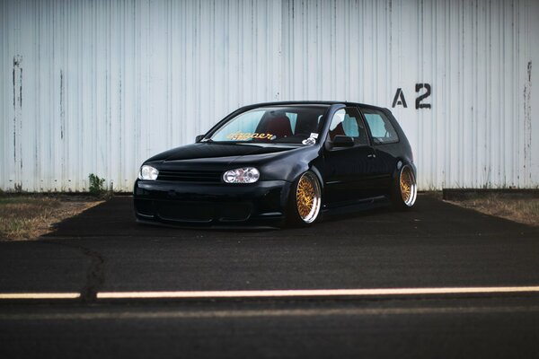 Black Volkswagen car on the background of a fence