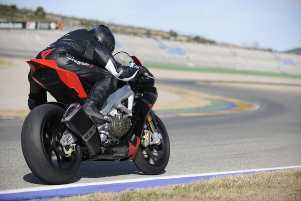 A man rides a black and red aprilia rsv4 sport bike