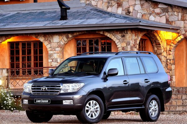 Czarna Toyota Land Cruiser na tle kamiennego domu z łukami