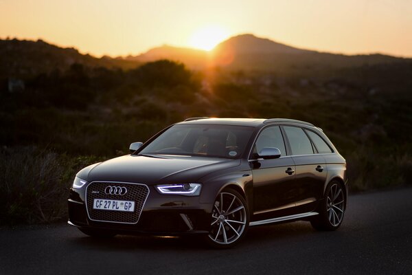 Audi RS4 negro en el fondo de la puesta de sol