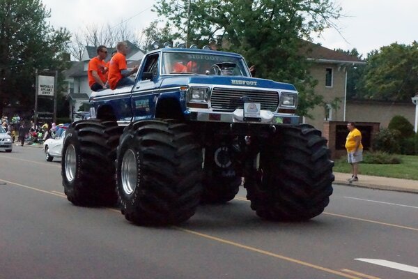 A jeep with huge wheels is driving on the road