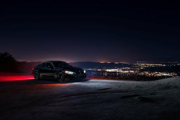 A car with neon lights stands on a deserted hill late in the evening