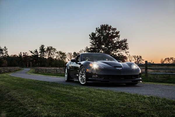 Coche negro al atardecer en la valla