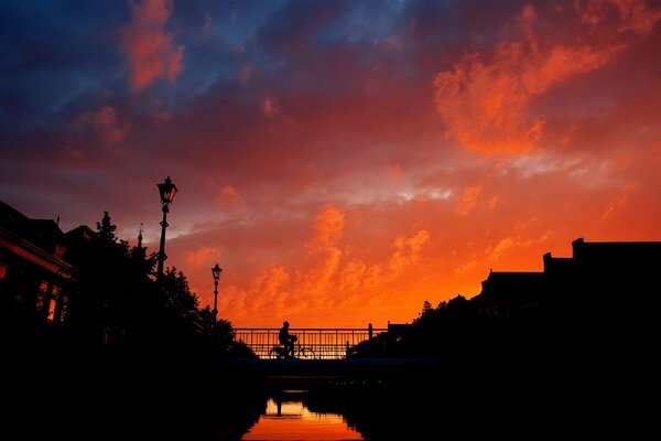 A cyclist rides on a bridge during sunset