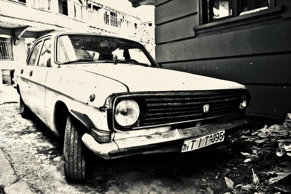 L auto GAZ 24 con un faro rotto si trova vicino alla casa