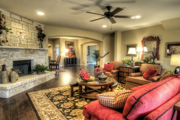 Living room with sofa and armchairs, table, carpet and fireplace, lots of vases and flowers