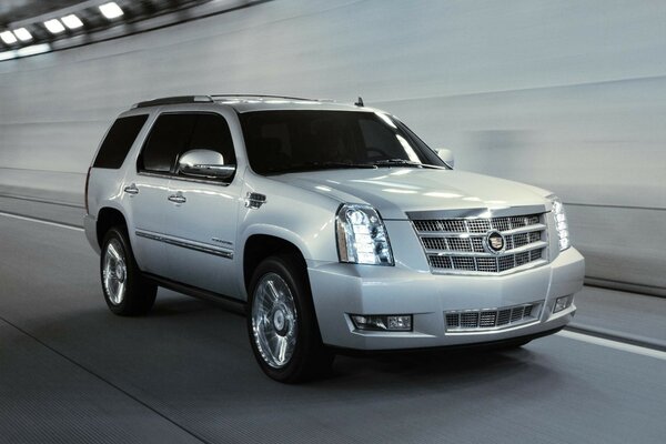 A gray Cadillac is driving at speed