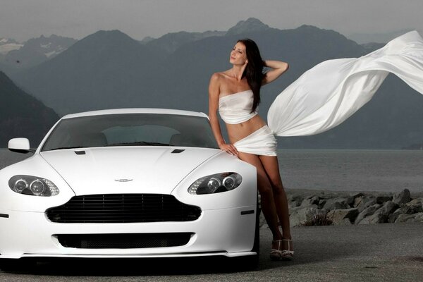 Voiture blanche Aston Martin. Fille en blanc près de la voiture. Route des montagnes