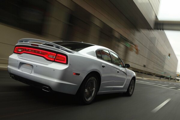 A white car is driving on the road against the background of the city