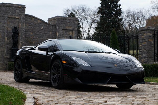 Lambirghini nero su sfondo muro di pietra