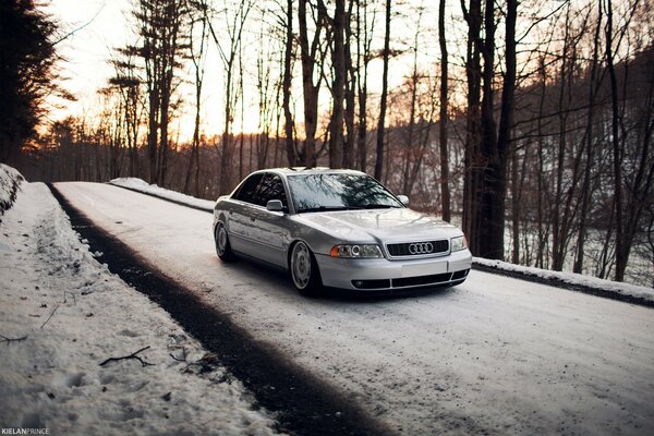 Srebrny Audi A4 snow forest road