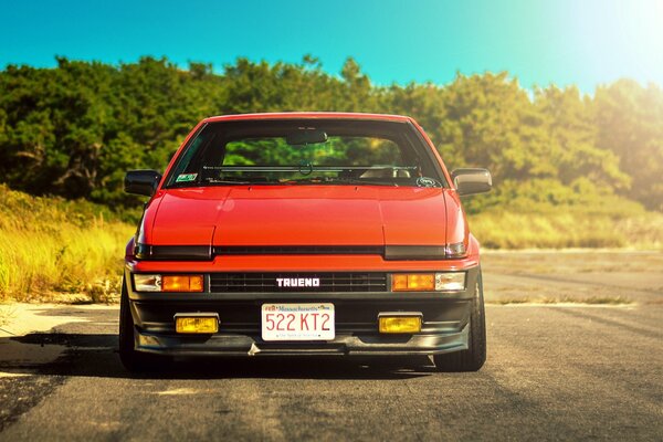 A red Toyota is driving on the road