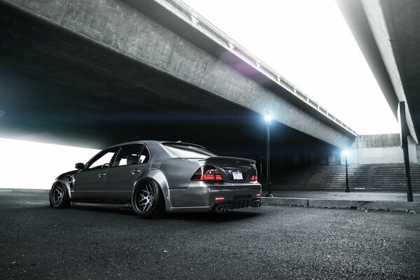 A tuned Toyota under the bridge next to a burning lantern of bright blue color